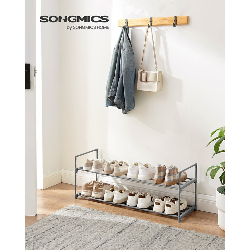 Grey shoe rack in a hallway holding shoes below a wall-mounted coat rail