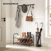 Black 2 tier shoe rack in a hallway under wall hooks, holding boots and shoes