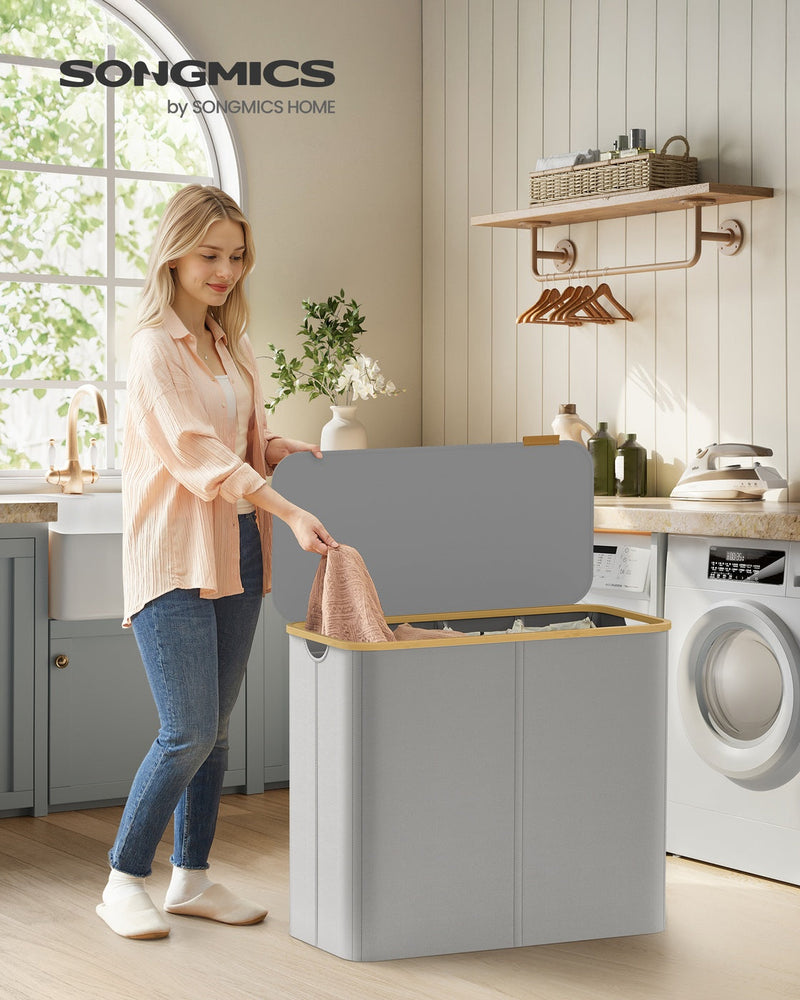 Woman lifting the lid of the grey laundry basket in a laundry room beside a washing machine