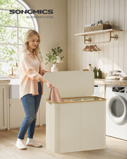 Woman lifting the bamboo trimmed lid of the cream laundry basket in a bright utility room