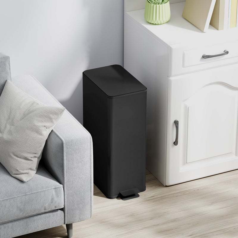 Black 20L slim stainless steel pedal bin closed beside a sofa and white cabinet