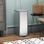 Silver 20L slim stainless steel pedal bin closed in front of a rattan cabinet and side table