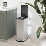Silver 20L slim stainless steel pedal bin with the lid open beside a houseplant