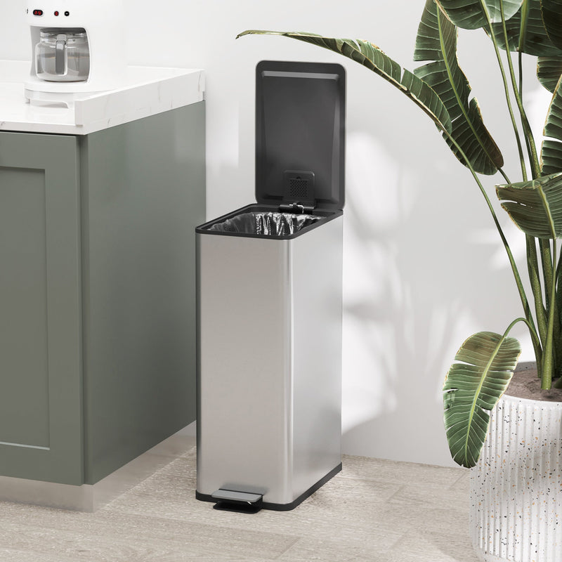 Silver 20L slim stainless steel pedal bin with the lid open beside a houseplant