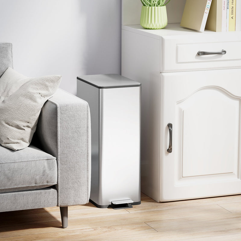Silver 20L slim stainless steel pedal bin closed beside a sofa and white cabinet