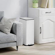 White 20L slim stainless steel pedal bin closed beside a grey sofa and white cabinet from a second angle