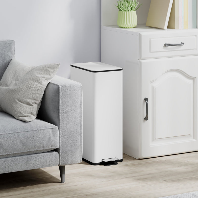 White 20L slim stainless steel pedal bin closed beside a grey sofa and white cabinet from a second angle