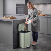 Woman scraping food into an open 20L pedal bin in a modern kitchen