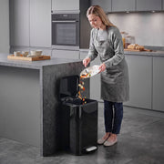 Woman scraping food into an open 20L pedal bin in a modern kitchen