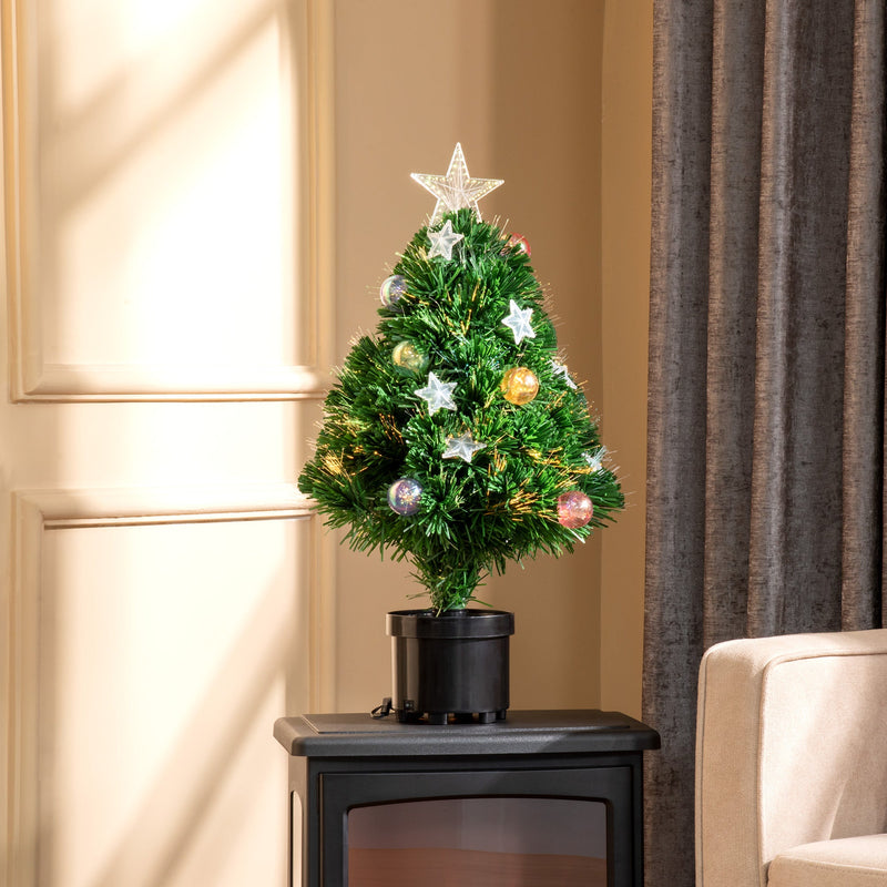 Tabletop tree on a black stove beside a cream armchair and curtain
