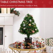 Tabletop tree on a glass table with red berries beside a fireplace