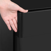 Close-up of a hand gripping the rounded edge of a black drawer front