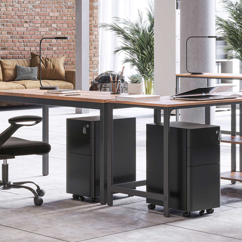 Two black filing cabinets rolled under a shared desk in a brick walled office