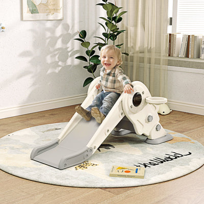 Toddler sliding down the cream white kids slide in a bedroom playroom