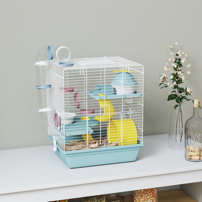 Blue 3-level hamster cage styled on a white shelf with dried flowers