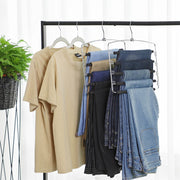 Trouser hangers holding folded jeans beside shirts on a black clothes rail