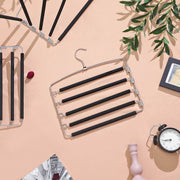 Flat lay of the trouser hanger on a peach background with clothes and a clock