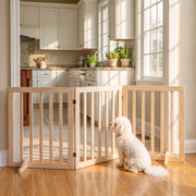 Small white dog sitting behind the natural pine freestanding dog gate in a kitchen doorway