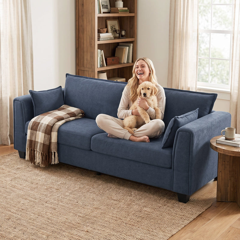 Woman holding a dog on the dark blue sofa next to a bookcase