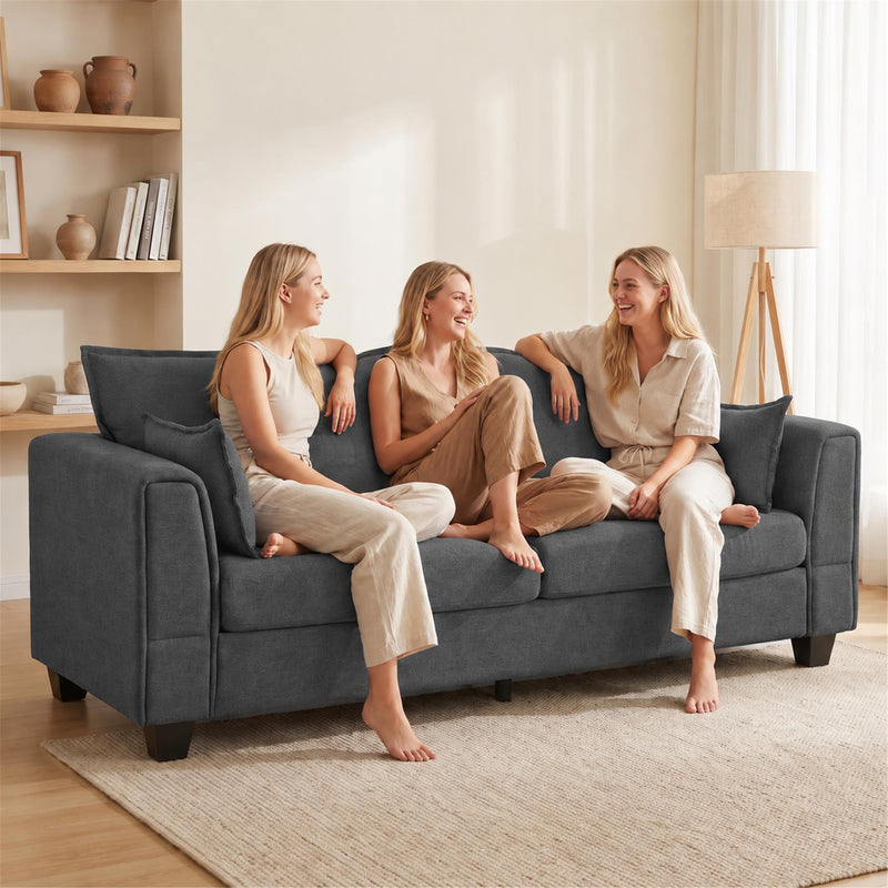 Three friends chatting on the dark grey 3 seater sofa in a bright living room