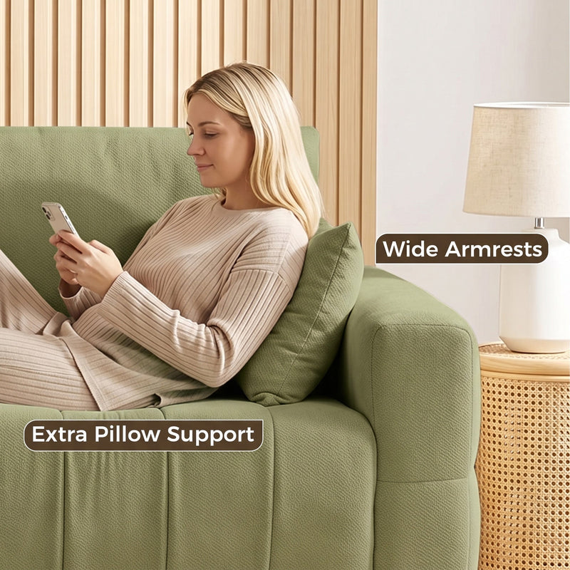 Woman relaxing against the wide armrest of the green sofa with an extra pillow