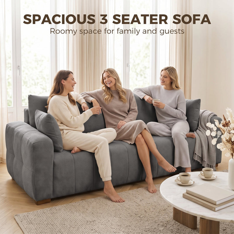 Three women chatting side by side on the grey 3 seater sofa
