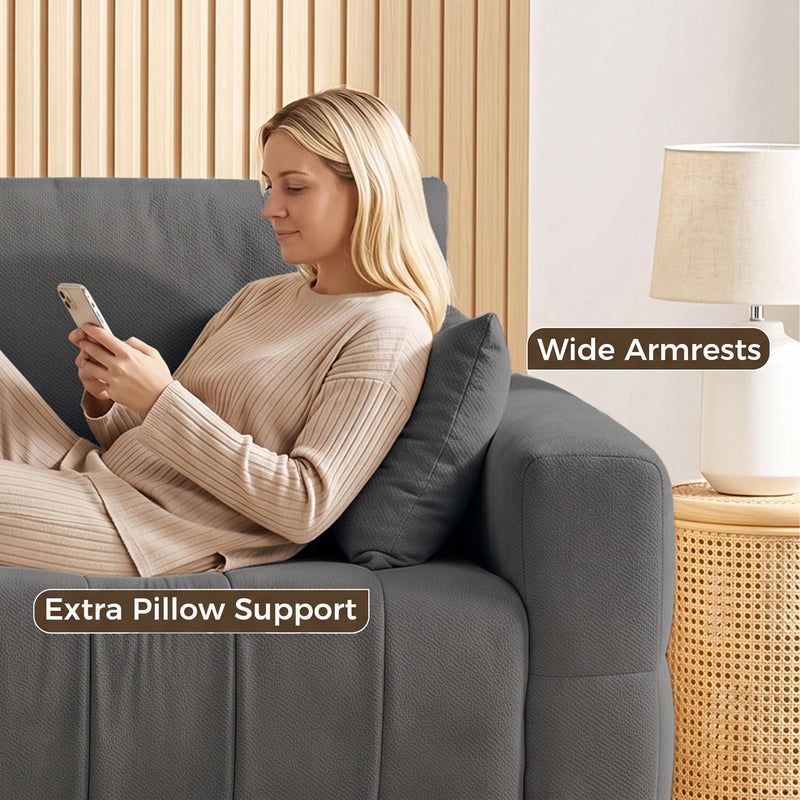 Woman relaxing against the wide armrest of the grey sofa with an extra pillow