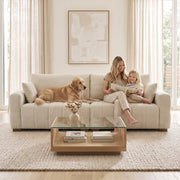 Family and dog on the cream white 3 seater sofa in front of a glass coffee table