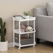 White trolley used as a side table beside a sofa with a tablet, plant and magazines
