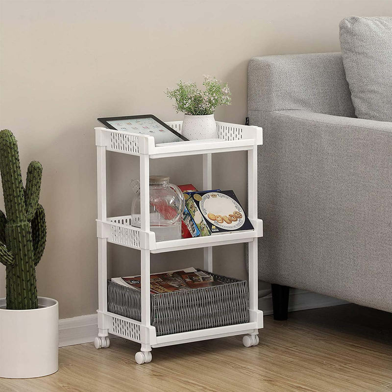 White trolley used as a side table beside a sofa with a tablet, plant and magazines