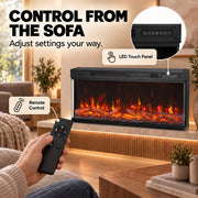 Hand holding the remote beside the LED touch panel close-up on the electric fire