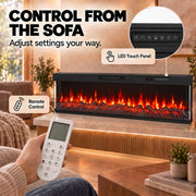Hand holding the remote beside the LED touch panel close-up on the electric fire