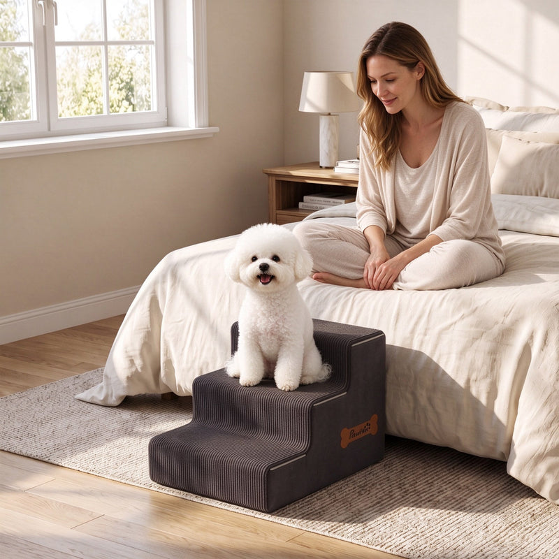 Small white dog sitting on the dog stairs beside a bed while a woman watches