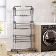 Grey 3-tier clothes airer standing empty next to a black washing machine