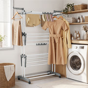 White clothes airer drying dresses beside a washing machine in a utility room