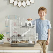 Boy standing beside the grey hamster cage on a sideboard at home