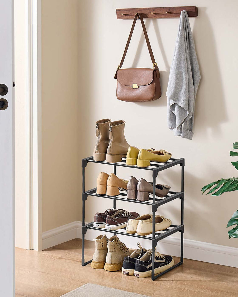 Black shoe rack holding boots and shoes in a hallway below a wall-mounted coat rack