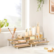 3-tier bamboo rack holding skincare bottles and make-up brushes on a bright bathroom worktop