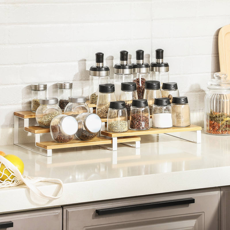 Bamboo spice rack filled with glass spice jars against white brick kitchen tiles