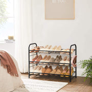 Black 3 tier shoe rack in a bedroom holding three rows of shoes beside a bed