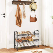 Black 3 tier shoe rack by a front door below a coat rail with a hat and bag