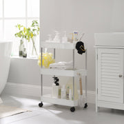 White storage trolley beside a bath holding towels, brushes and pump bottles