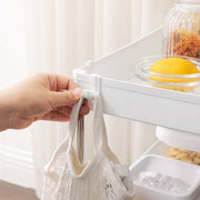 Close-up of a hand hanging a fabric bag on one of the trolley's clip-on side hooks