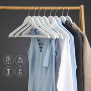 White wooden hangers on a wooden rail holding dresses, shirts and a coat