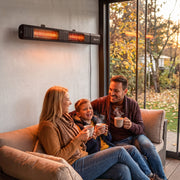 Family drinking hot drinks on a sofa beneath the wall-mounted heater by a window