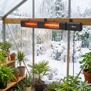 Heater mounted on a wooden beam warming potted plants in a snowy greenhouse