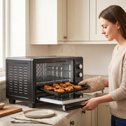 Woman removing a tray of chicken wings from the black 30L mini oven