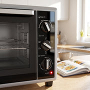 Close-up of the three control knobs and power light on the mini oven front panel