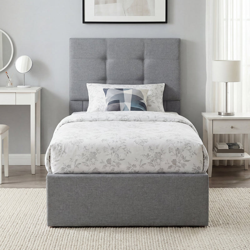 Grey upholstered ottoman bed made up with floral bedding in a bedroom setting