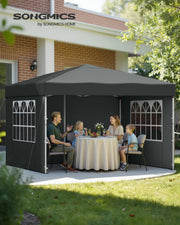 Family of four eating a meal at a round table under the dark grey gazebo in a garden